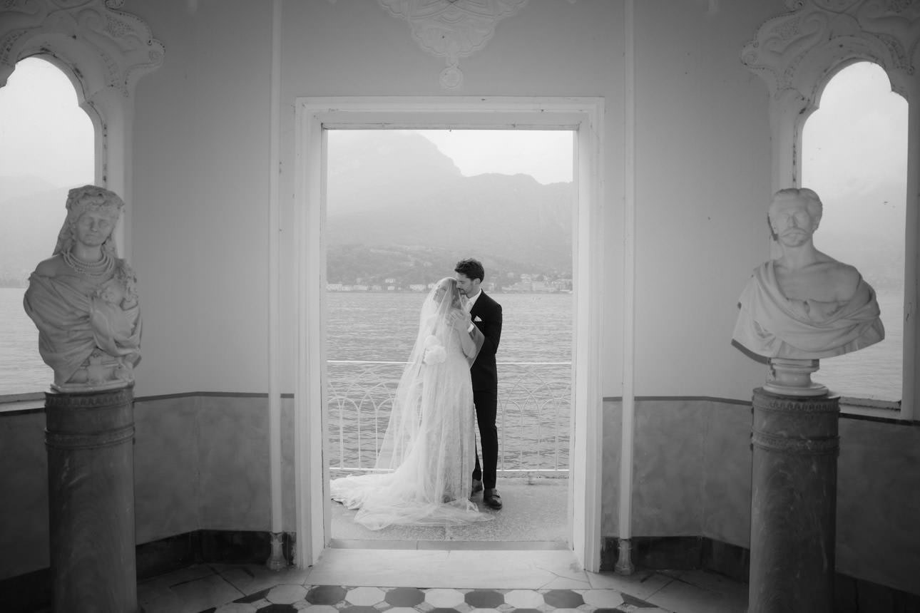 Bride and groom at their luxury wedding by a small temple in the gardens of Villa Melzi, Lake Como, Italy.