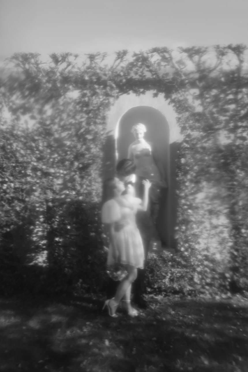Bride and groom pose in front of a statue in the beautiful gardens of Belvedere Palace during their wedding photoshoot in Vienna.