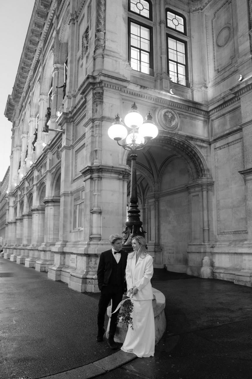 Bride and groom standing elegantly in front of the Vienna State Opera during an editorial wedding photoshoot in Austria.