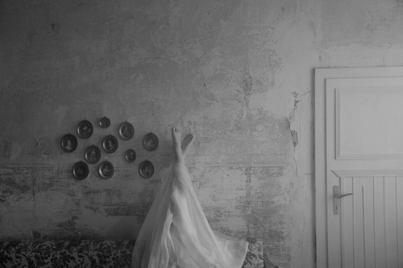 Bride’s legs leaning against an old wall of a villa, capturing a relaxed and elegant moment during her wedding.