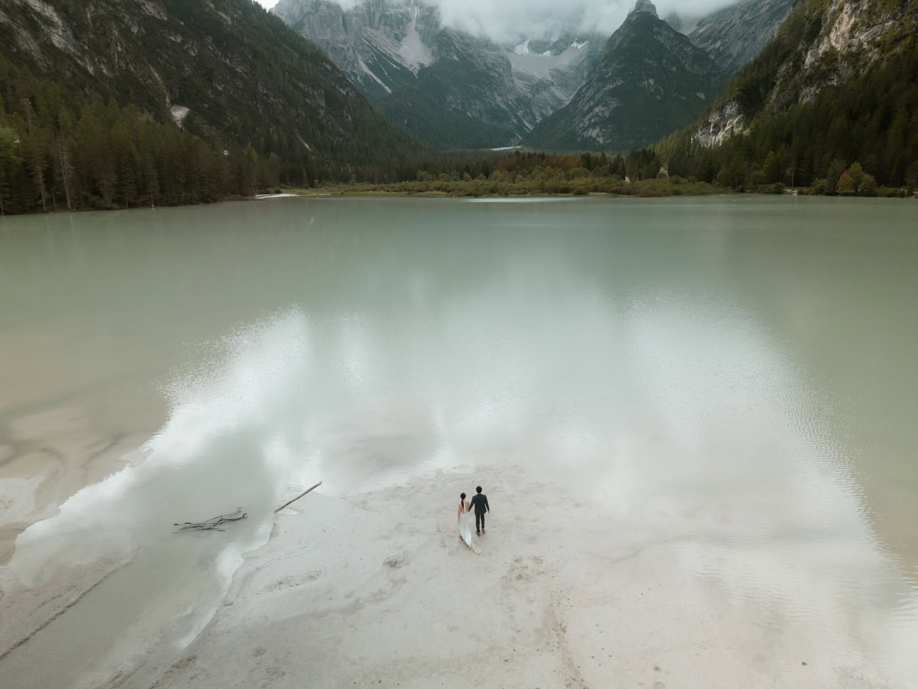 Elopement couple gazing at Lago di Landro in the Dolomites, surrounded by stunning natural beauty on their intimate wedding journey.