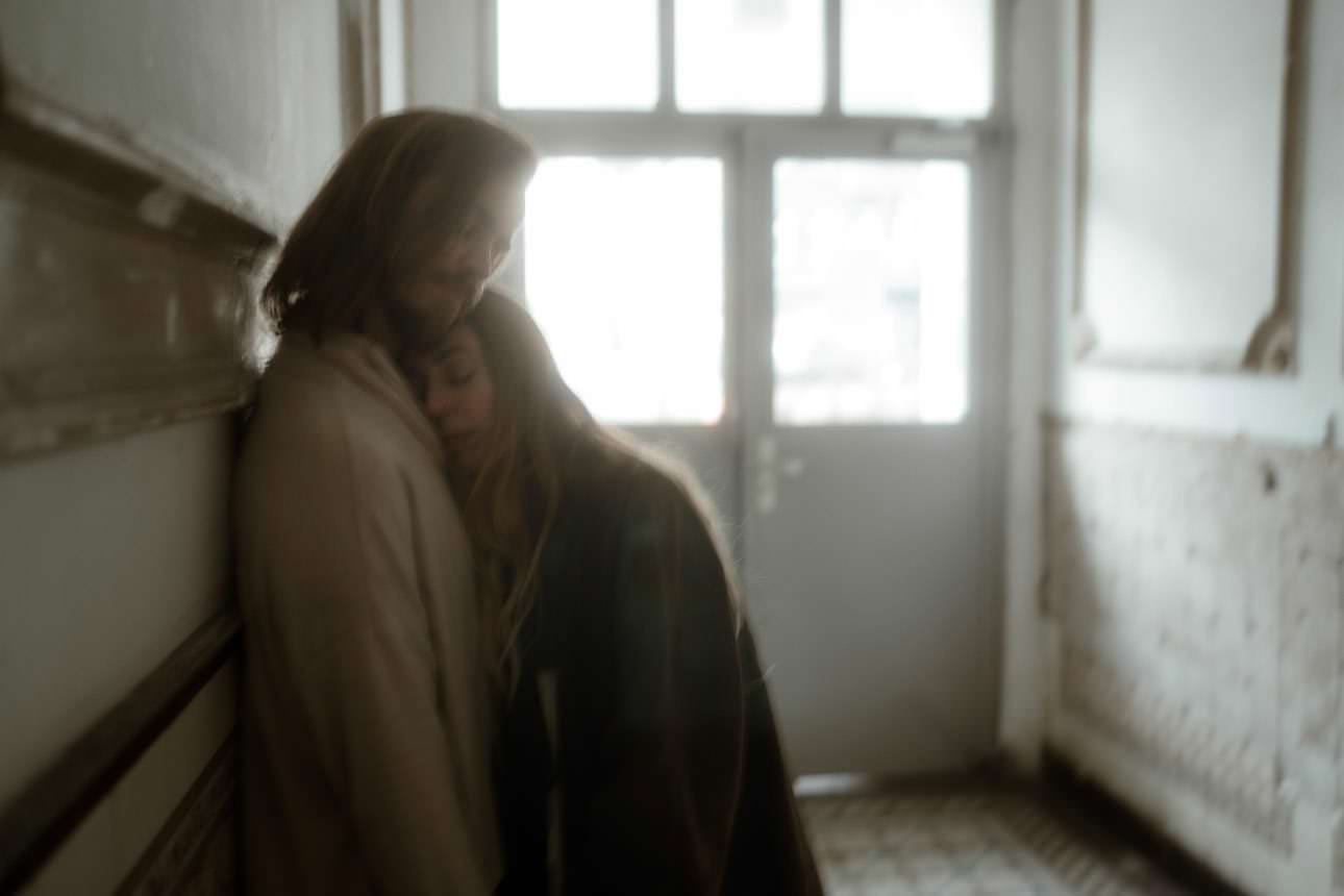 Girlfriend leaning against her boyfriend in a staircase in Berlin, capturing a tender and intimate moment.