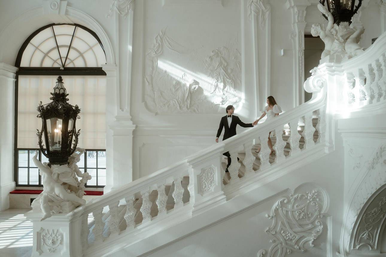 Groom leading his bride down the stairs at Belvedere Palace for their wedding photos, capturing a tender and elegant moment.