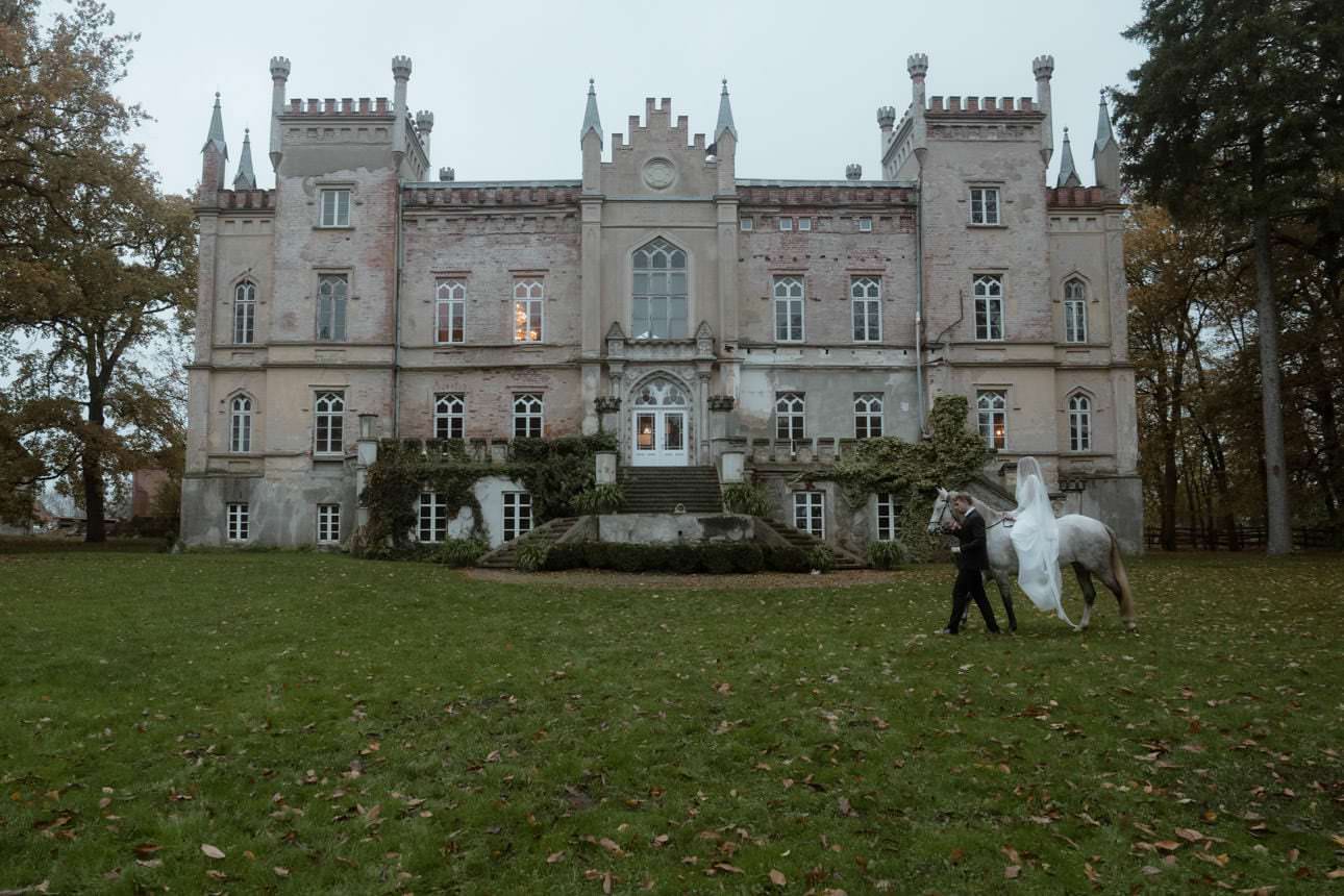 Groom leading his bride on a horse during a wedding at a historic castle in Germany, creating a fairytale-like scene.