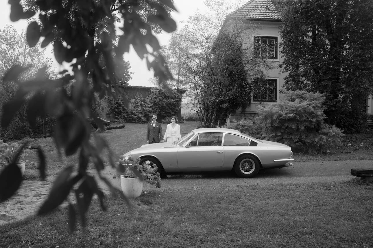Wedding couple standing behind a green Ferrari Oldtimer during a stylish wedding photoshoot, blending luxury and elegance.