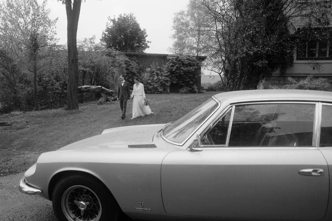 Wedding couple walking toward their Ferrari Oldtimer at a luxurious wedding, capturing an elegant and timeless moment.